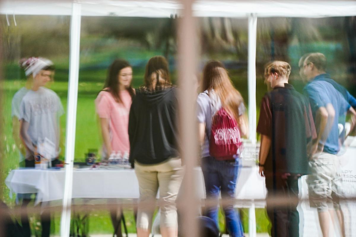 students standing at a table, talking reflection in window